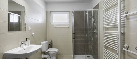 Un baño moderno con lavamanos, inodoro y ducha con mampara de vidrio.