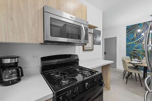 A modern kitchen with a stainless steel microwave, a black stove, and a coffee maker.