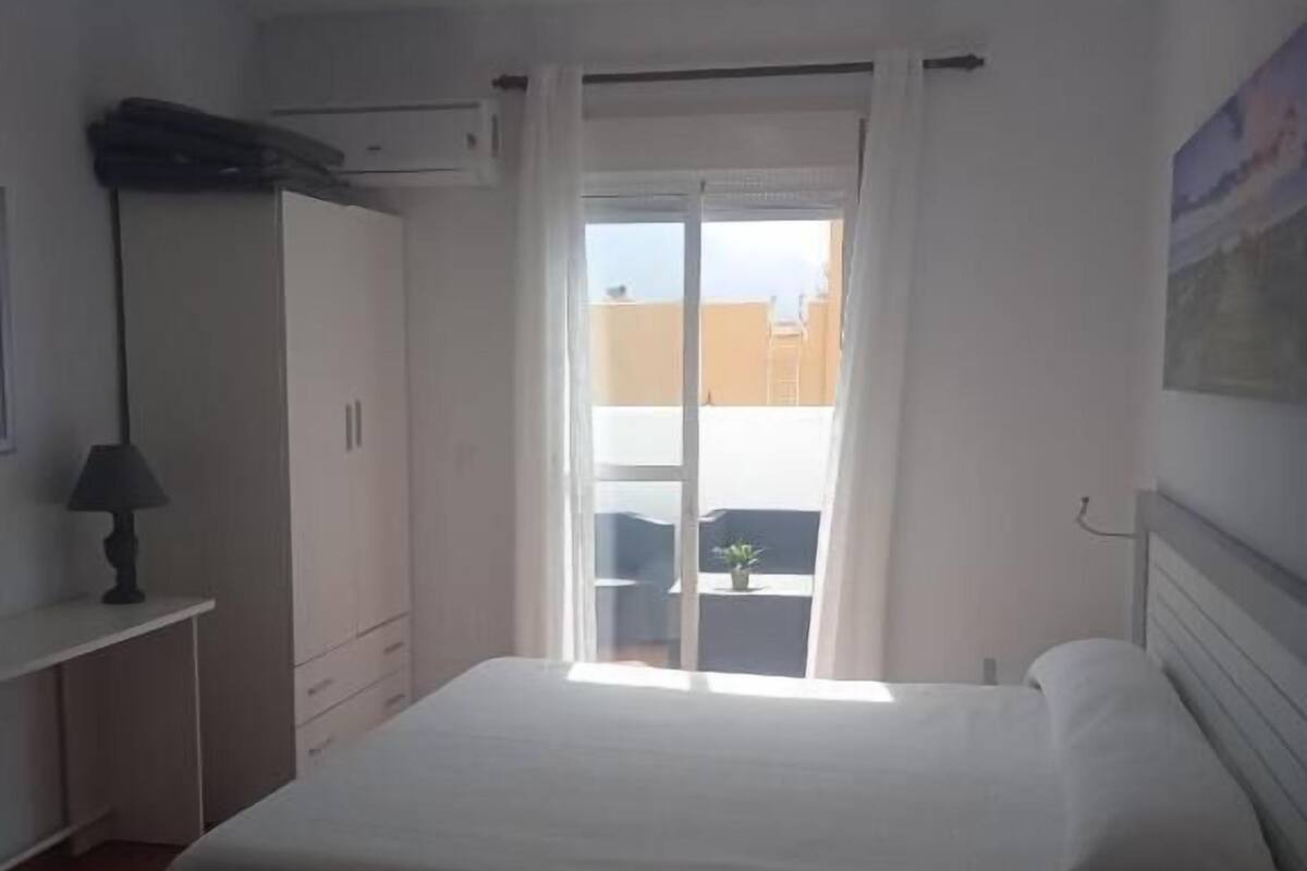 Habitación de hotel con cama, escritorio, armario y vistas al exterior.