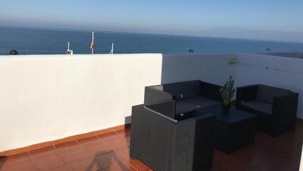 Eine Dachterrasse mit Meerblick, ausgestattet mit Sitzgelegenheiten, Kissen und einem kleinen Tisch.