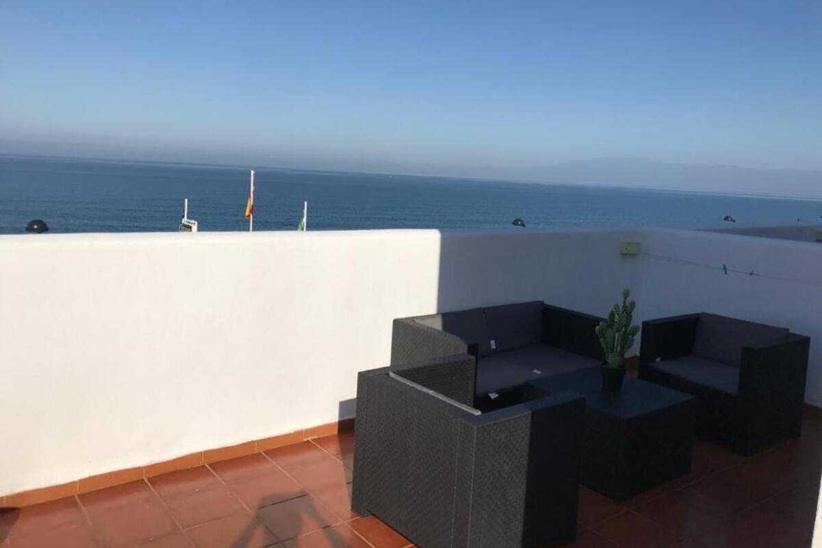 Una terraza en la azotea con vista al mar, que incluye una zona de estar con cojines y una mesita.