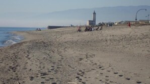 Ein Strand mit Fußspuren, einem Turm und einigen Personen.