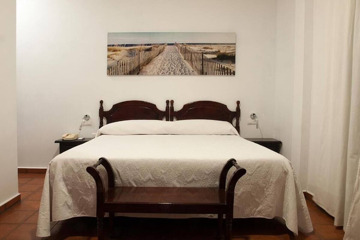Un dormitorio con una cama de madera, una mesita de noche y un banco.