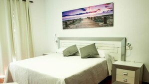 Ein Schlafzimmer mit Bett, Nachttisch, Sessel und einem an der Wand hängenden Bild.