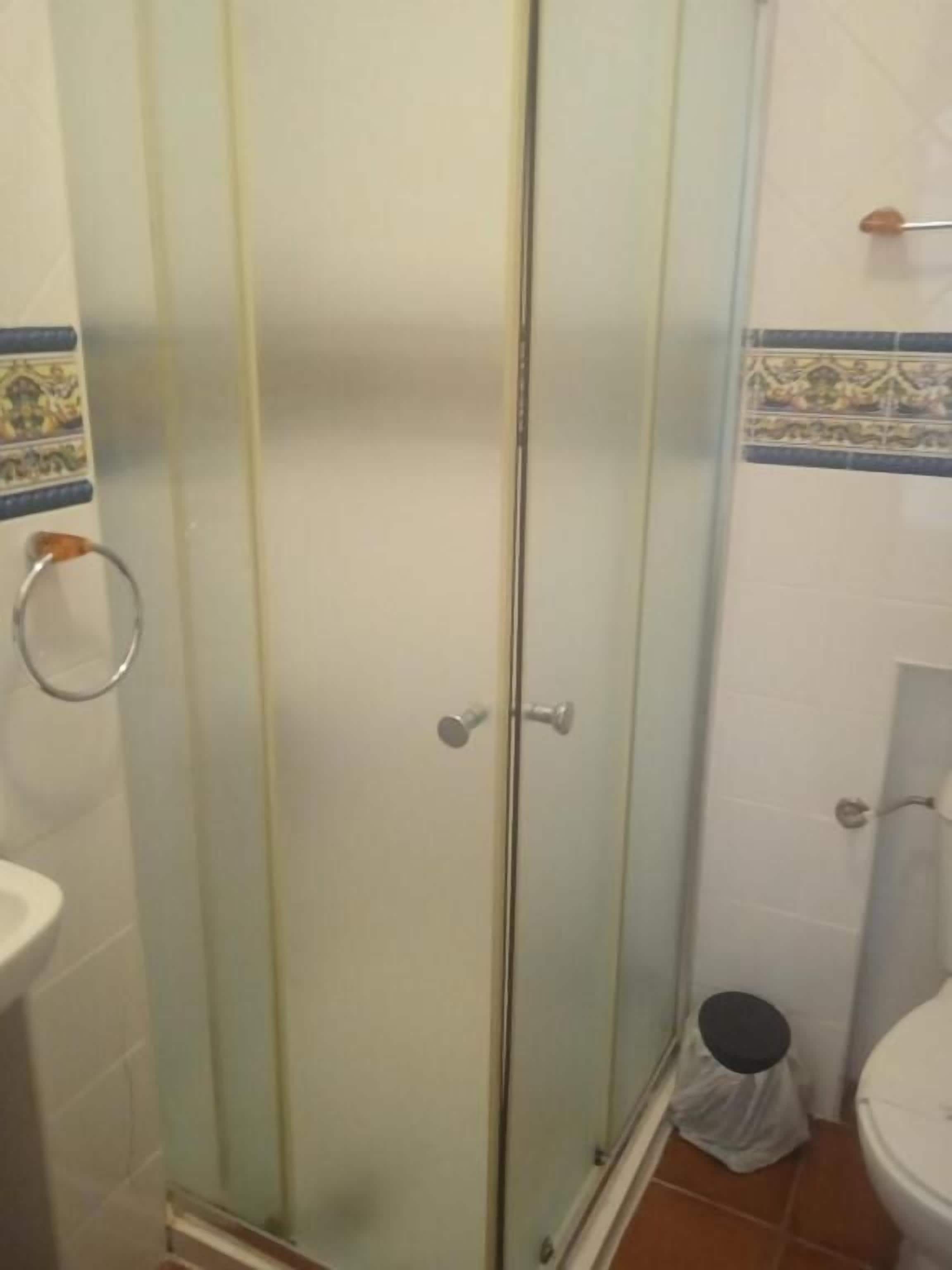 A bathroom with a glass-enclosed shower, a toilet, and a sink.