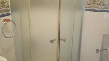 A bathroom with a glass-enclosed shower, a toilet, and a sink.
