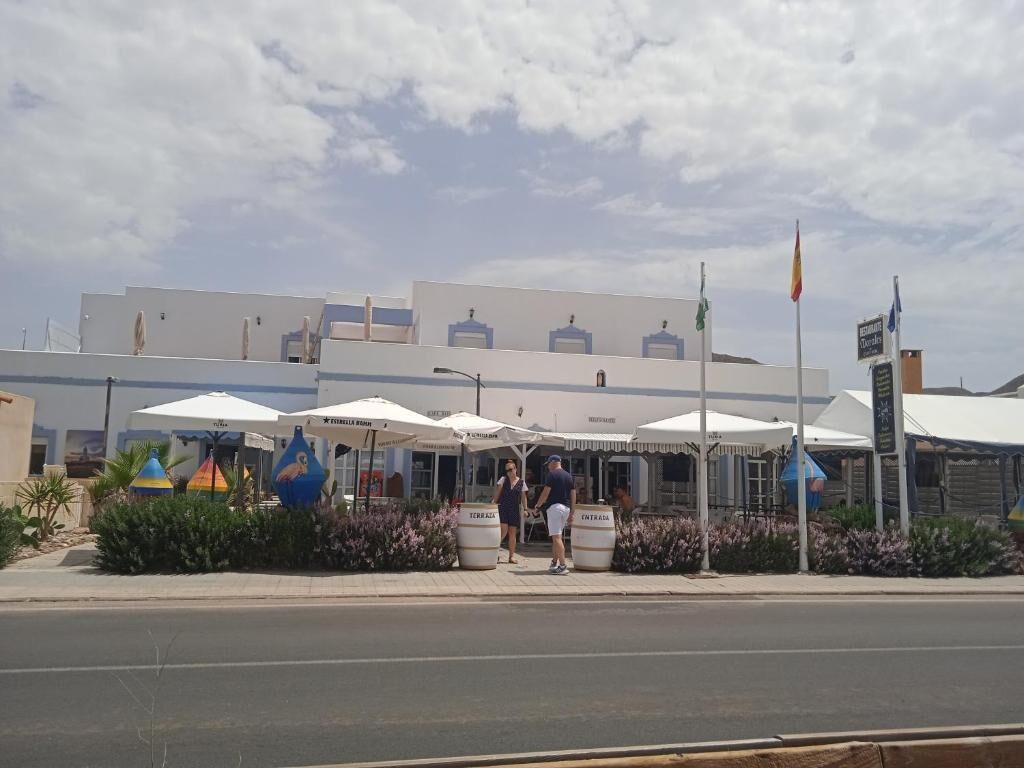 A building with outdoor seating and umbrellas, a flag, and a signboard.