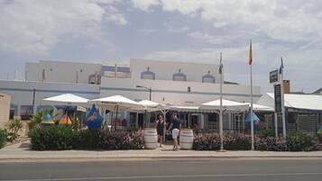 A building with outdoor seating and umbrellas, a flag, and a signboard.