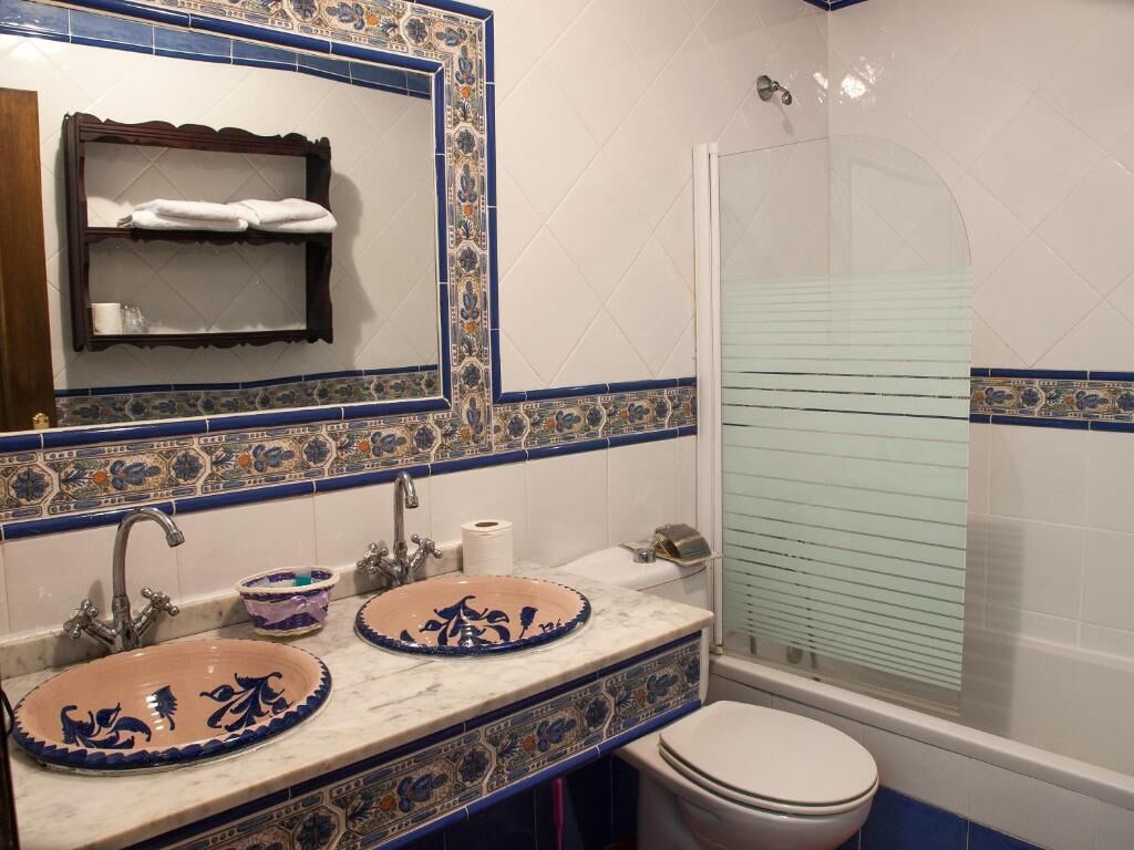 A bathroom with two sinks, a toilet, a shower, and a mirror.