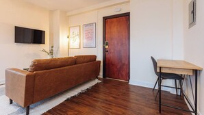 Un salon avec un canapé marron, une table en bois et un téléviseur fixé au mur.