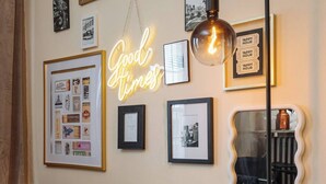 Une pièce décorée d’un néon lumineux sur lequel on peut lire « Good Times », d’un collage encadré et d’un miroir fixé au mur.