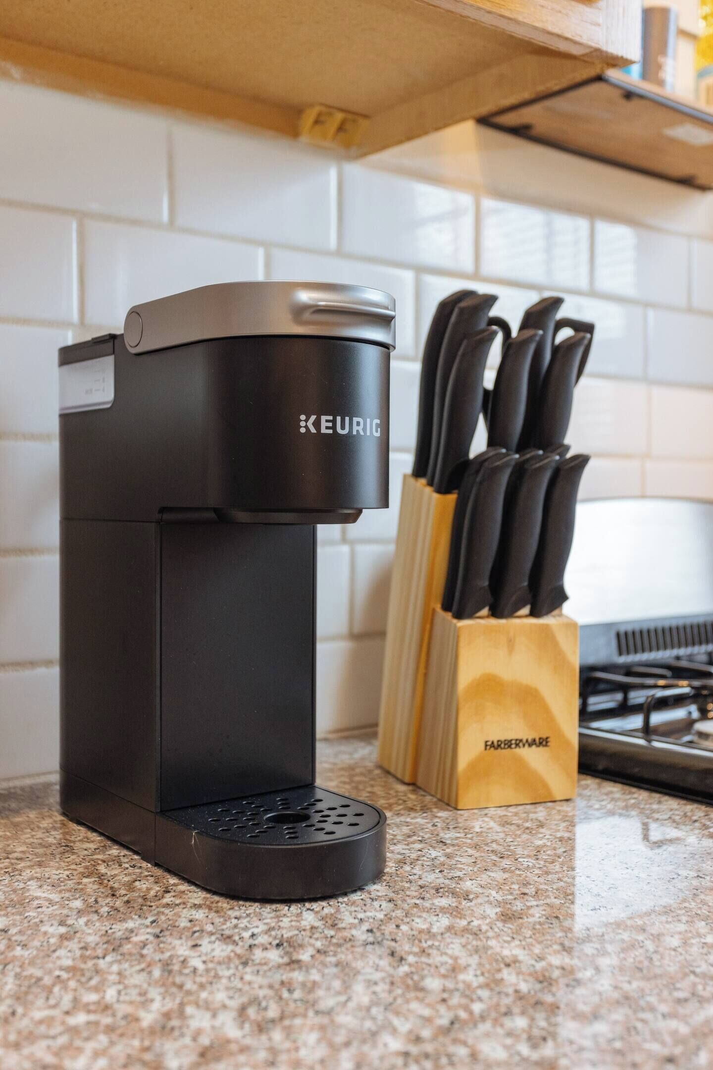 A Keurig coffee maker on a kitchen counter with a Farberware knife block.