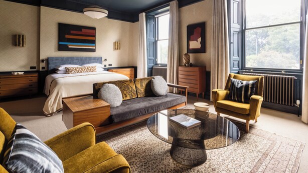 A modern hotel room with a bed, sofa, armchair, and a glass coffee table. - 3 Johns Place Townhouse (Edinburgh)