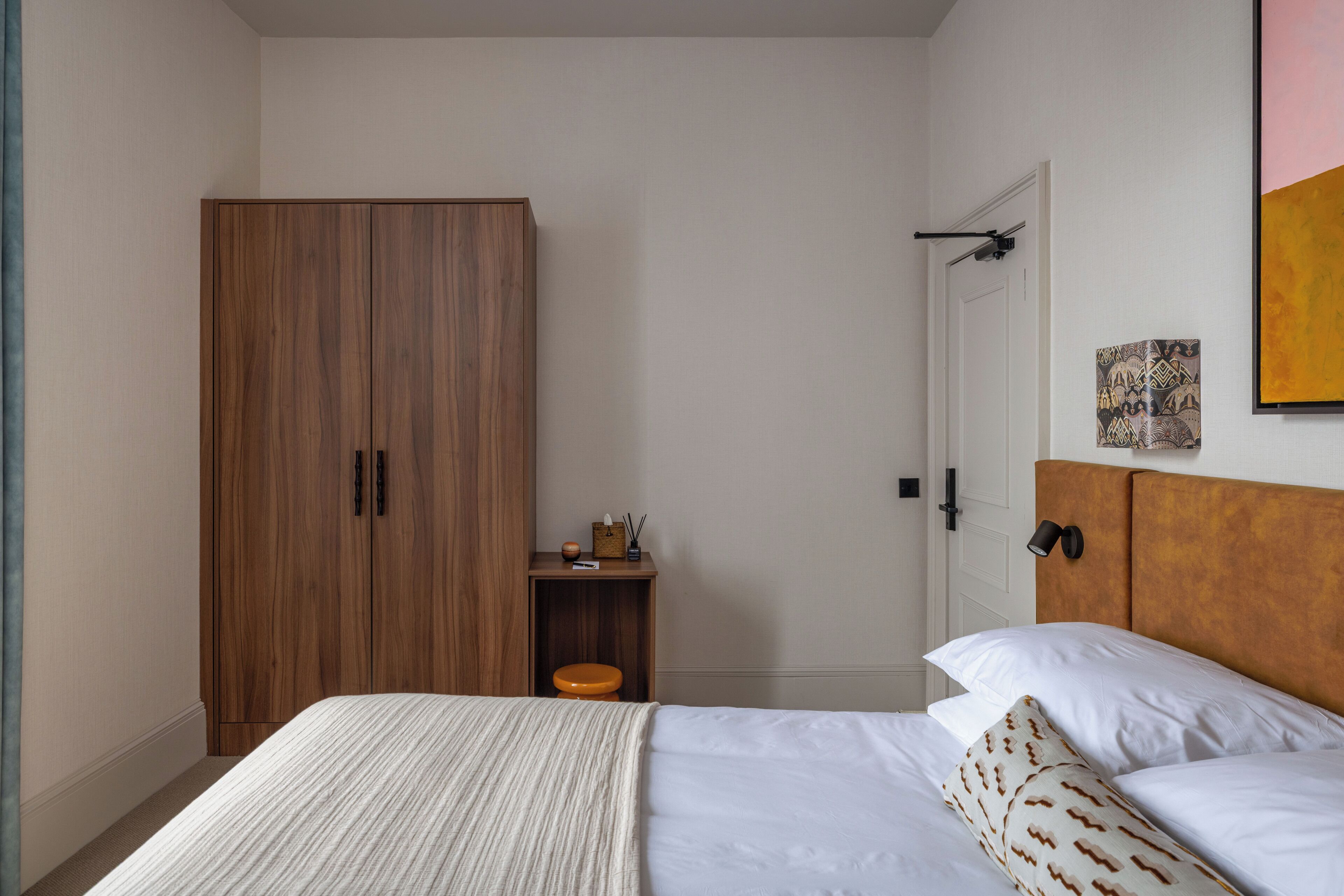 Un dormitorio con cama, armario de madera, mesita de noche y cabecero.