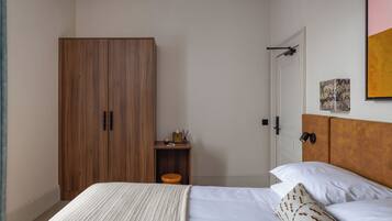 Un dormitorio con cama, armario de madera, mesita de noche y cabecero.