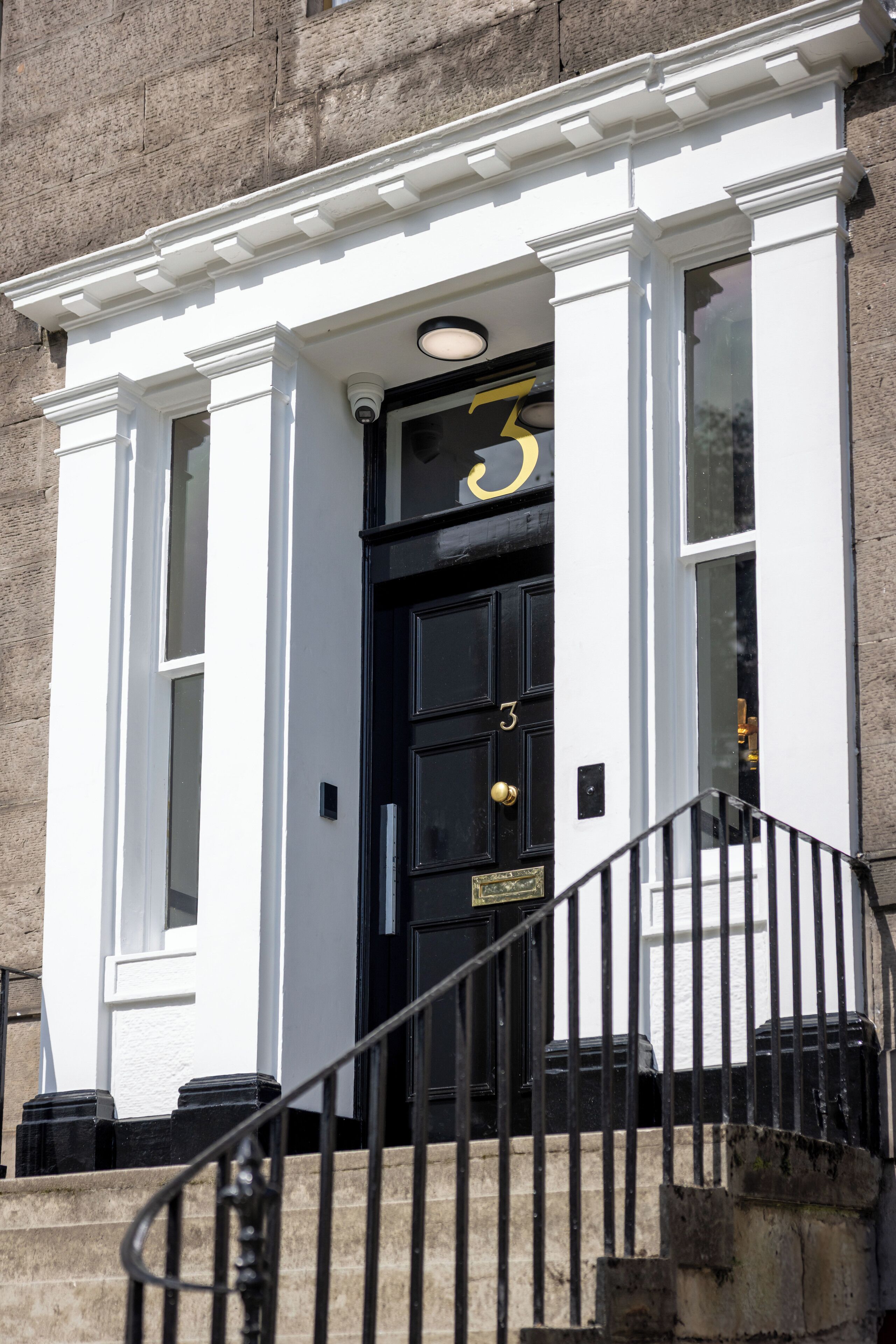 A building with a black door marked with the number 3, white trim, and a small window above the door.