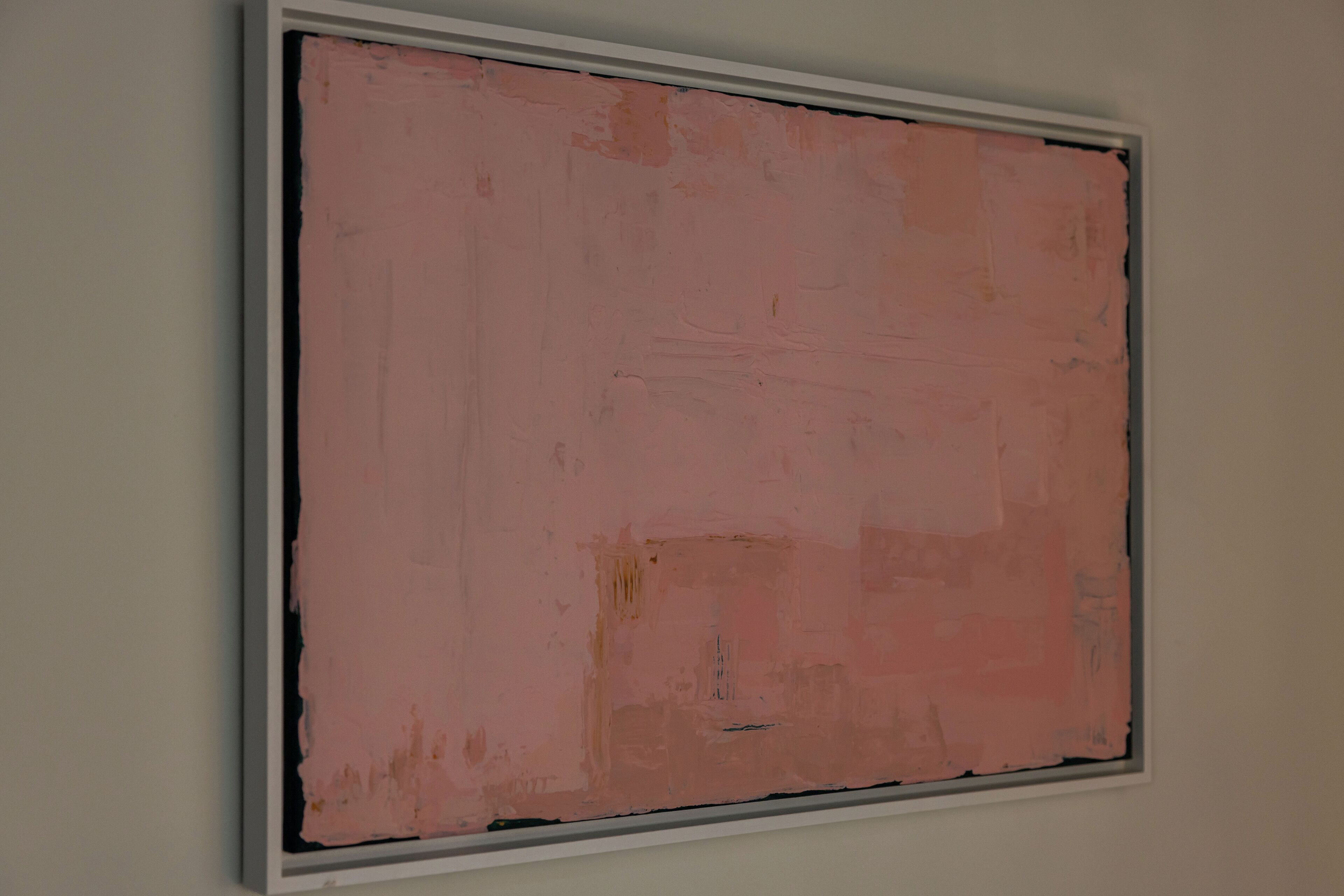 Una obra d'art rectangular de grans dimensions i superfície rugosa, penjada a una paret senzilla.