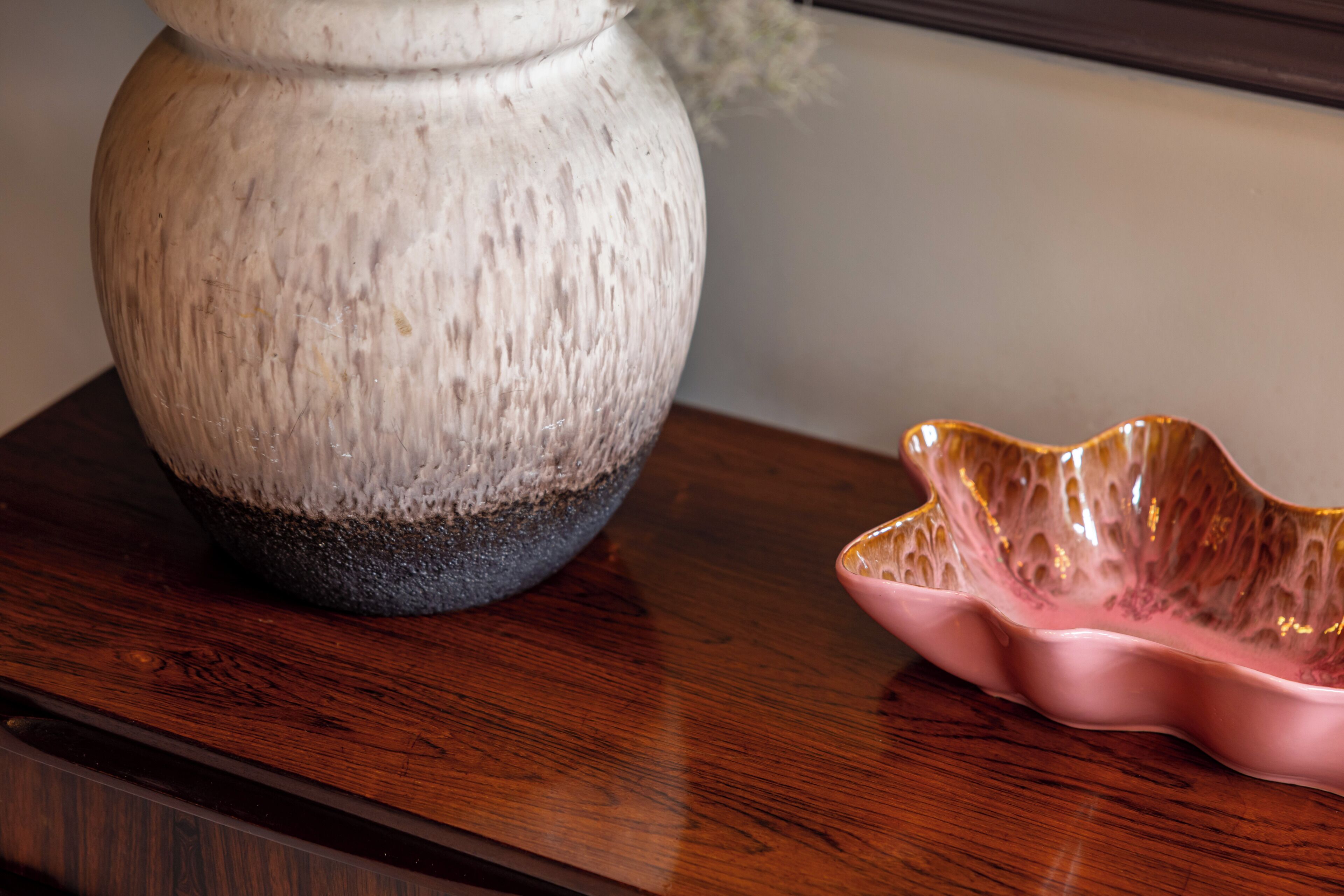 Ein Holztisch mit einer weißen Vase und einer pinkfarbenen Dekoschale.