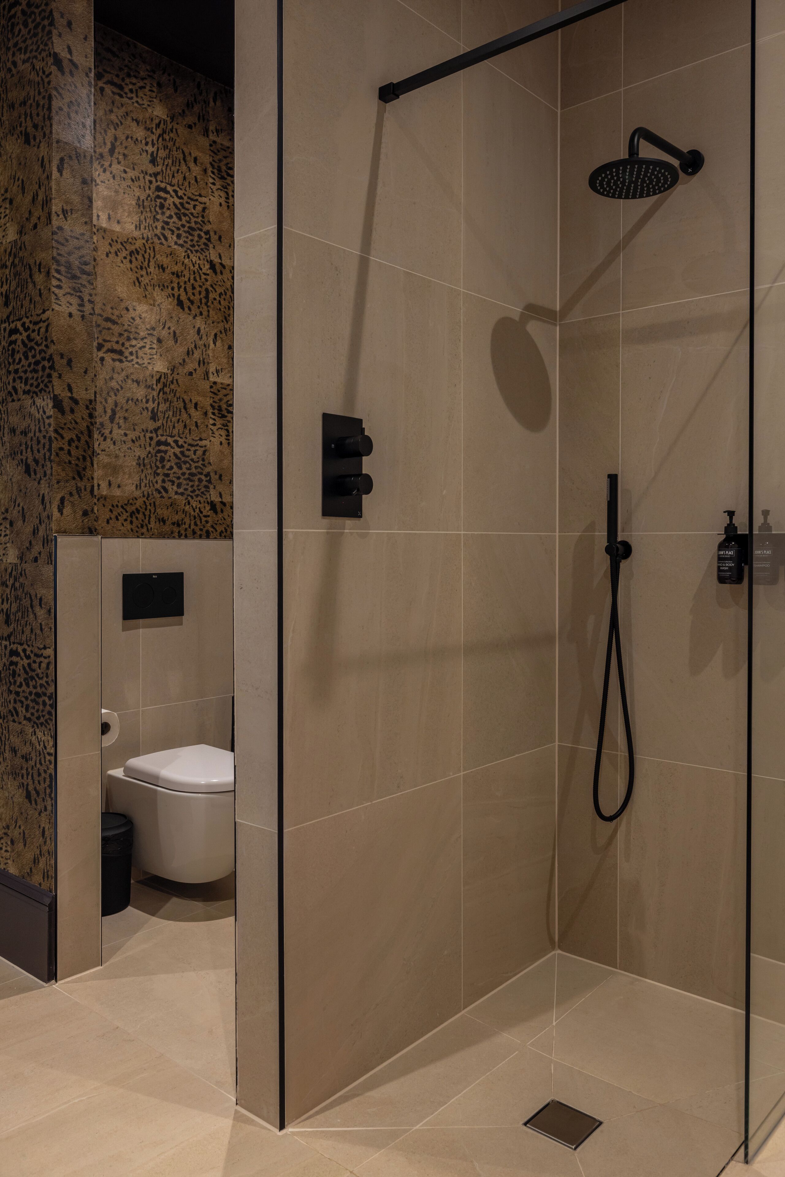 Un bany modern amb plat de dutxa tancat amb vidre, un vàter i un lavabo.