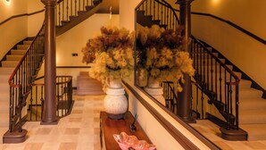 A grand staircase with a polished wooden finish and black balusters, flanked by large white vases with dried foliage. - 3 Johns Place Townhouse (Edinburgh)