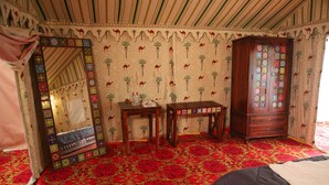 Una habitación con un espejo grande, un armario de madera y piso cubierto de alfombra roja.