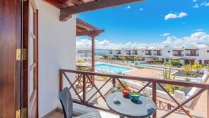 A balcony with a view of a swimming pool and hotel buildings. - Casa del Mar Ilic - Communal pool, Sea Views, 10 Minutes to Marina Rubicón (Playa Blanca)