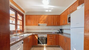 A kitchen with wooden cabinets, a built-in oven, a dishwasher, and a refrigerator. - Casa del Mar Ilic - Communal pool, Sea Views, 10 Minutes to Marina Rubicón (Playa Blanca)