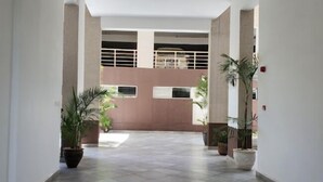A hallway with a tiled floor, potted plants, and a large gate in the background. - Staroot Residences (Nairobi)