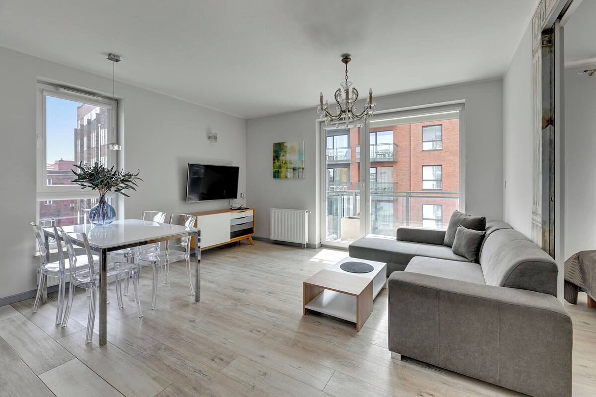 A modern living room with a sofa, coffee table, and dining area with chairs.