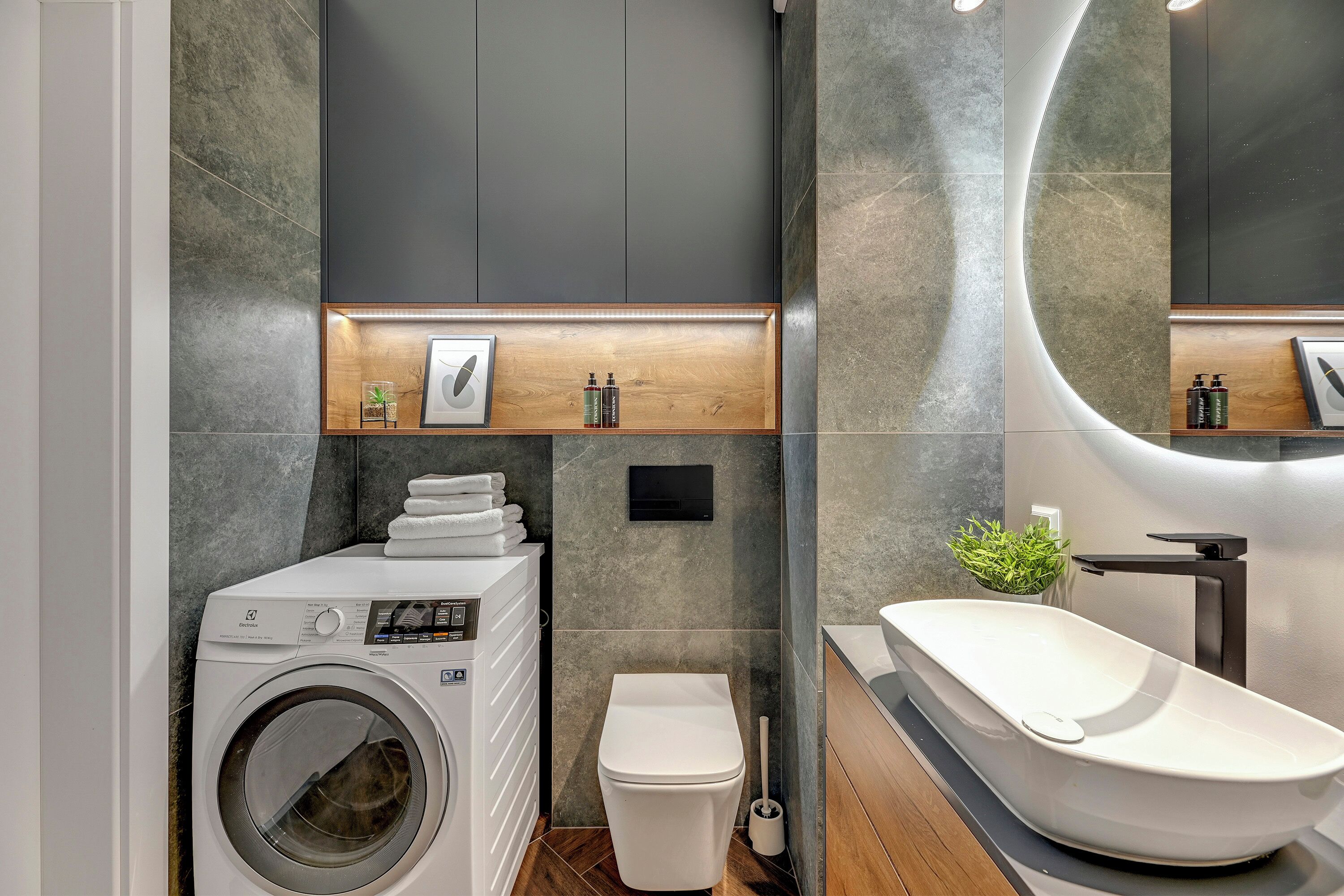 A modern bathroom with a built-in washing machine, a toilet, and a freestanding bathtub.
