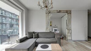 A modern living room with a grey sectional sofa, a white coffee table, and a wooden side table. -  Bastion Wałowa City Center & Parking by Downtown Apartments (Gdansk)