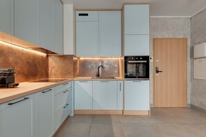 Una cocina moderna con armarios de colores claros, un lavamanos de acero inoxidable y un horno empotrado.