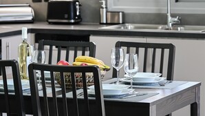 A modern kitchen with a dining table set for two, featuring a bottle of wine, a banana, and a bowl of fruit. - Charming Villa Penelope with Private Pool walking distance to Lefkada town (Lefkada)