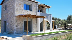 A two-story stone house with a balcony, a pergola, and a patio area with outdoor seating. - Charming Villa Penelope with Private Pool walking distance to Lefkada town (Lefkada)