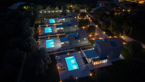An aerial view of a residential area with multiple houses, each featuring a swimming pool and a well-lit driveway. - Cosy Halipoma-Tilemahos into Lefkada town & close to Ai Giannis beach (Lefkada)