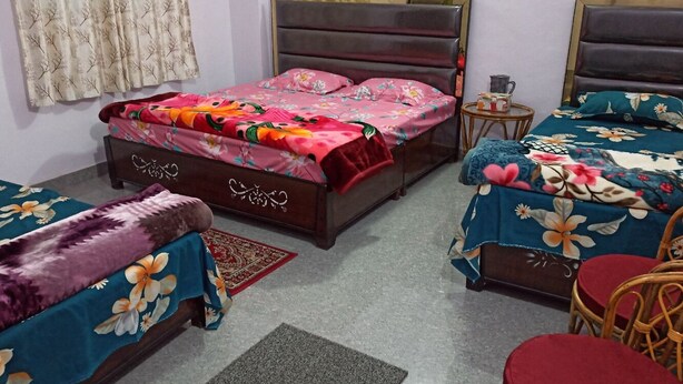 A hotel room with two single beds, a sofa, a small table, and a chair. - Indralok Hotel By GRB (Jakholi)