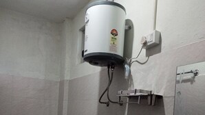 A bathroom with a toilet, bidet, sink, and a water heater mounted on the wall. - Indralok Hotel By GRB (Jakholi)