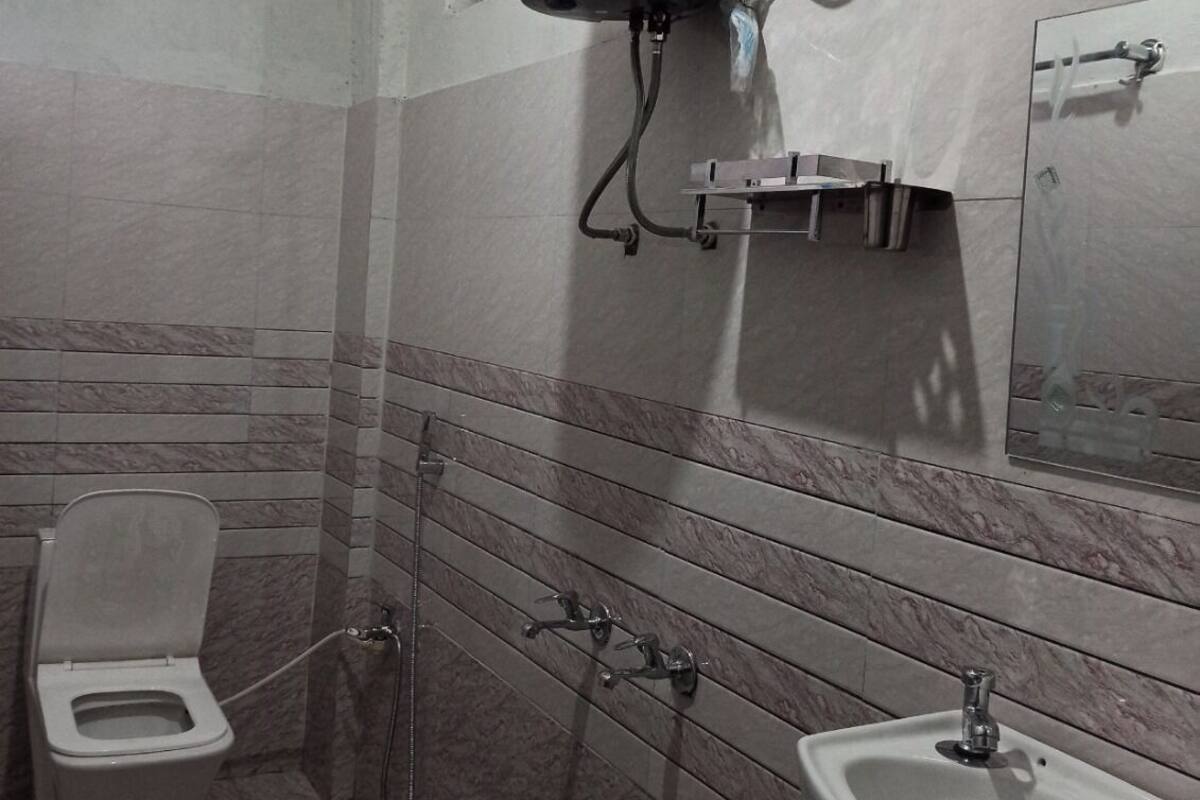 Une salle de bain équipée de toilettes, d’un bidet, d’un lavabo et d’un chauffe-eau fixé au mur.