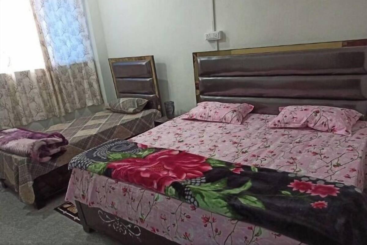 Une chambre à coucher avec un lit, une table de chevet, une chaise et une fenêtre avec des rideaux.