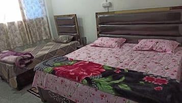 A bedroom with a bed, a nightstand, a chair, and a window with curtains.