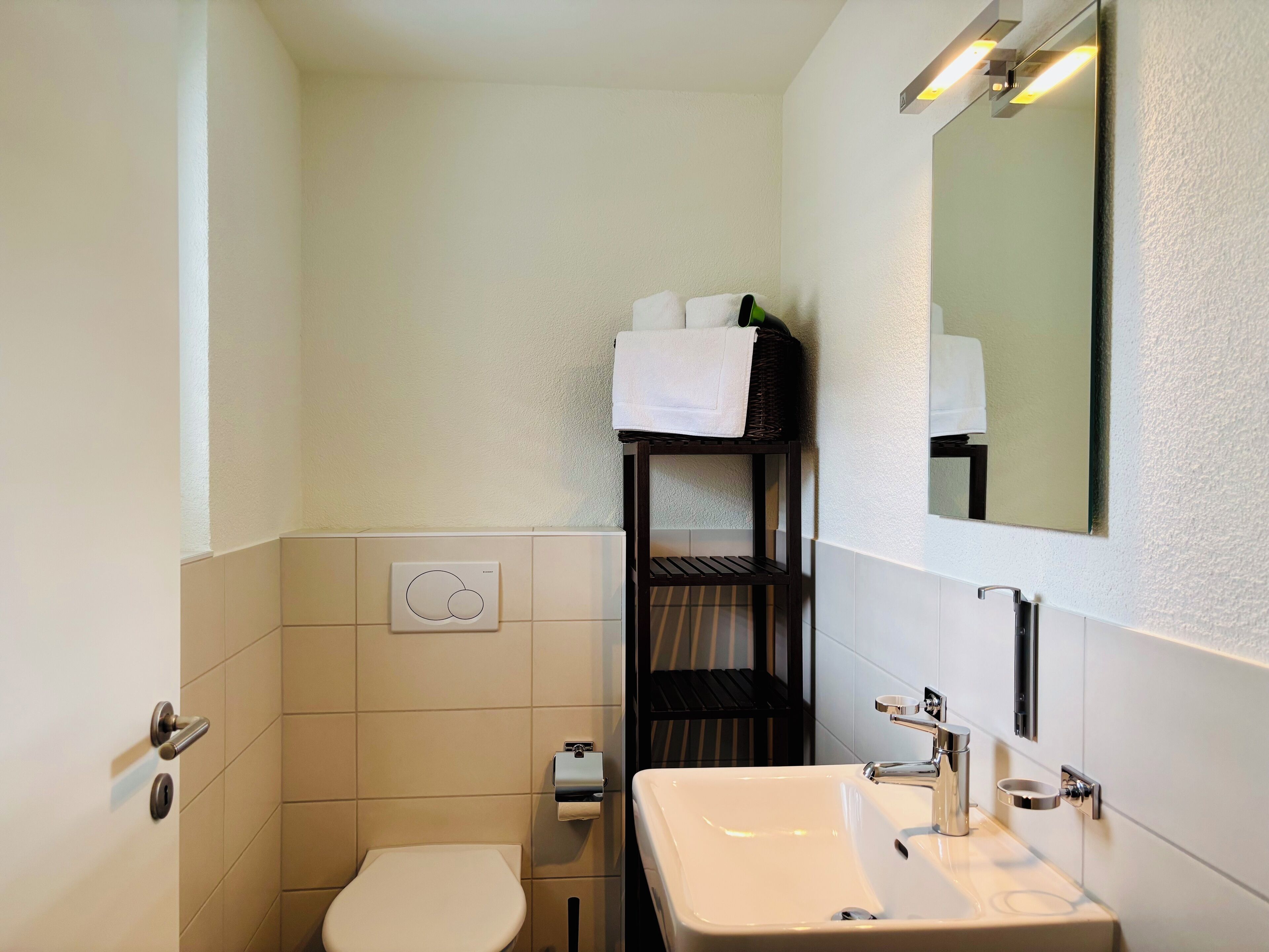 Une petite salle de bain comprenant des toilettes, un lavabo et un porte-serviettes avec des serviettes.