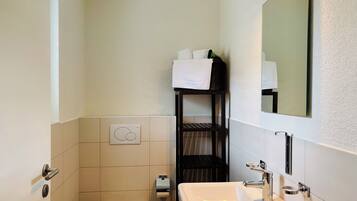 Une petite salle de bain comprenant des toilettes, un lavabo et un porte-serviettes avec des serviettes.
