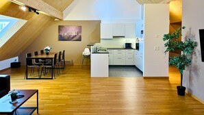 A modern loft with a dining area, kitchen, and a large skylight. - TONIGHT Apartments (Bottmingen)