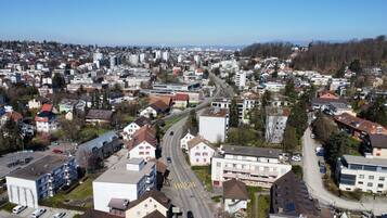 Een woonwijk met een combinatie van appartementencomplexen en huizen, met een hoofdstraat waar voertuigen rijden en voetgangersoversteekplaatsen zijn.