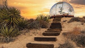 Um caminho leva a uma estrutura em forma de cúpula geodésica em uma paisagem desértica.