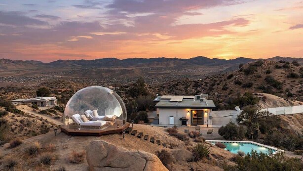 Uma casa com piscina, uma estrutura em forma de cúpula e vista para a paisagem ao redor.