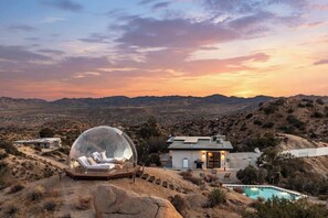 A house with a swimming pool, a dome-shaped structure, and a view of the surrounding landscape.
