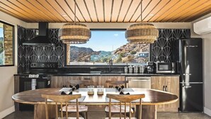Cozinha moderna com uma ilha grande, eletrodomésticos pretos e vista para uma paisagem montanhosa.