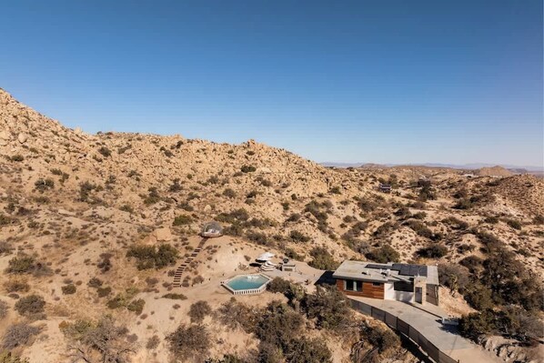 A desert landscape with a modern house featuring a swimming pool and a patio area.