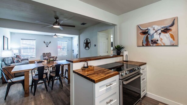 A modern kitchen with a wooden countertop, built-in oven, and a dining area with a table and chairs. - The Azure Escape Summ (Corpus Christi)